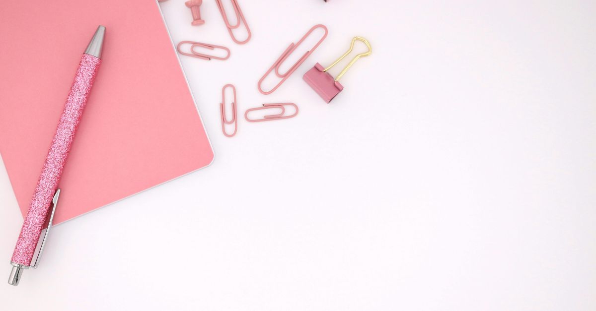 Büroklammern, Stift und Notizblock auf einem leicht rosa Hintergrund. Titel "Smart - Ziele"